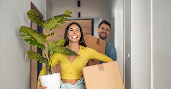 a man and a woman holding boxes and a plant
