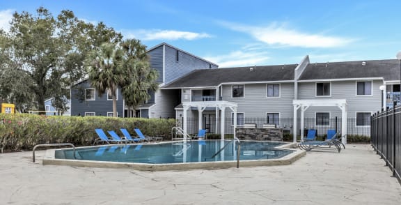 a large swimming pool in front of a building with palm trees