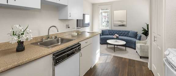 A kitchen with white cabinets and a wooden floor.