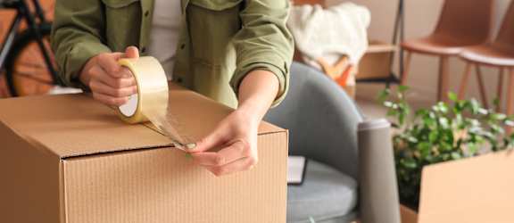 A person is taping a cardboard box.