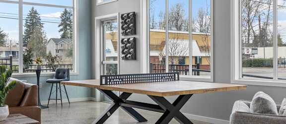 a ping pong table in a living room with large windows