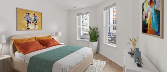 A bedroom with a bed, nightstand, and two paintings on the wall.
