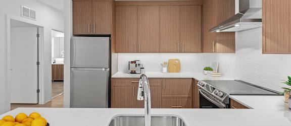 A modern kitchen with a stainless steel sink and wooden cabinets.