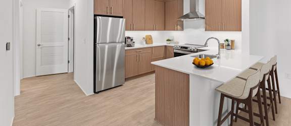 A modern kitchen with a white island and wooden cabinets.