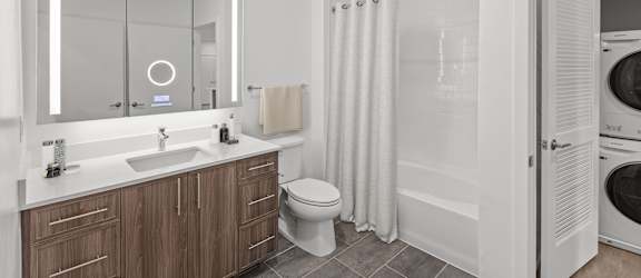 A modern bathroom with a wooden vanity and white fixtures.