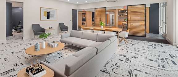 A modern living room with a grey sofa, a coffee table, and a patterned carpet.