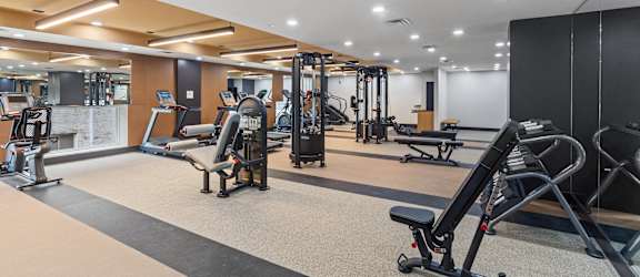 A gym with a variety of equipment including treadmills, weights, and exercise machines.