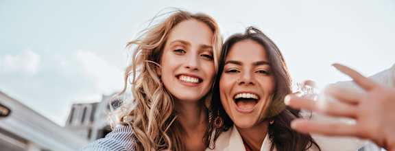 Two women are making a peace sign with their hands.