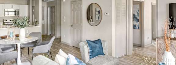A living room with a grey couch and a round mirror on the wall.