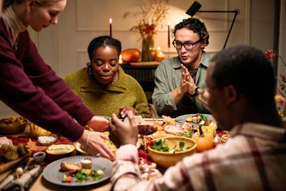 A group of people are gathered around a dinner table with various dishes.