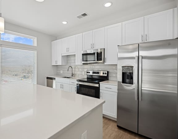 a large white kitchen with stainless steel appliances and white counter tops