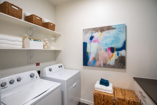 a washer and dryer in a laundry room with a painting on the wall