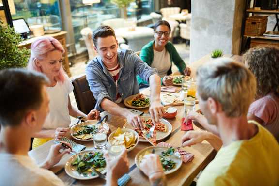 A group of people are sitting around a table enjoying a meal together.