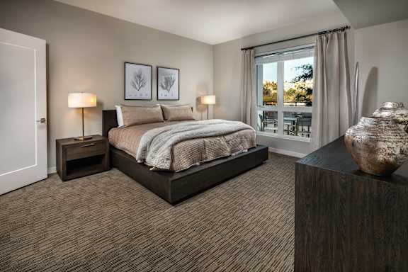 A bedroom with a large bed and a wooden nightstand.