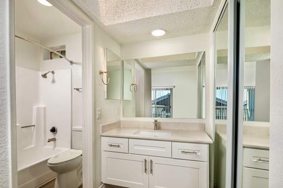 A white bathroom with a toilet, sink, and mirror.