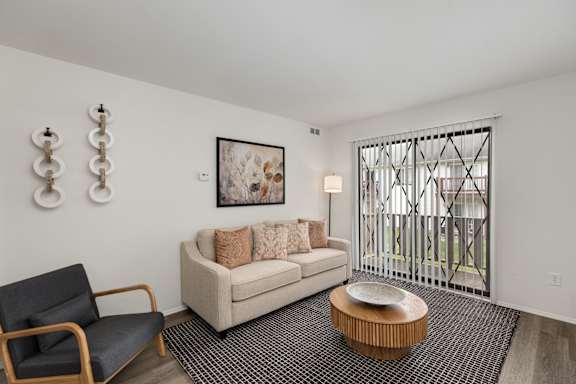 A living room with a couch, chair, and a painting on the wall.