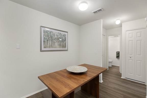 A room with a wooden table and a painting on the wall.