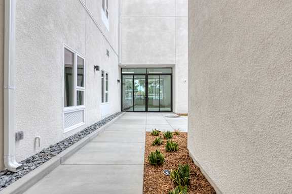 A modern building with a glass door entrance and a small garden in front.