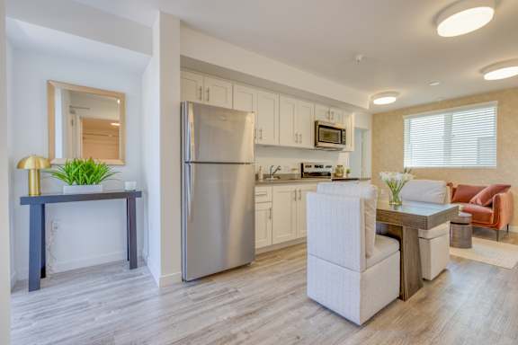 A modern kitchen with a stainless steel refrigerator and a dining table with chairs.