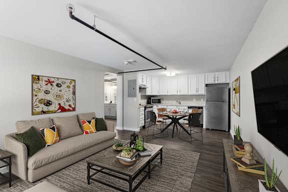 A living room with a couch, a coffee table, and a kitchen in the background.