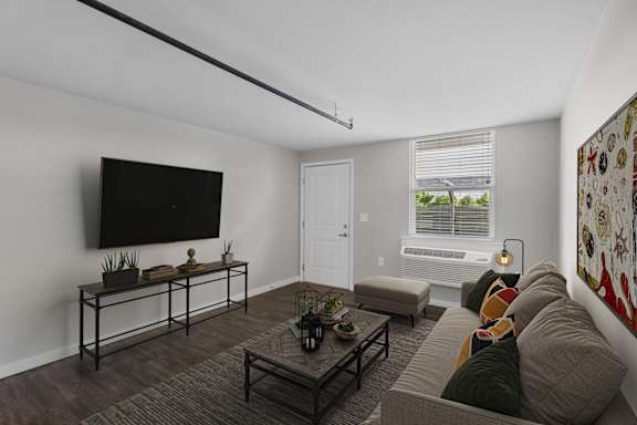 A living room with a grey couch and a black television.