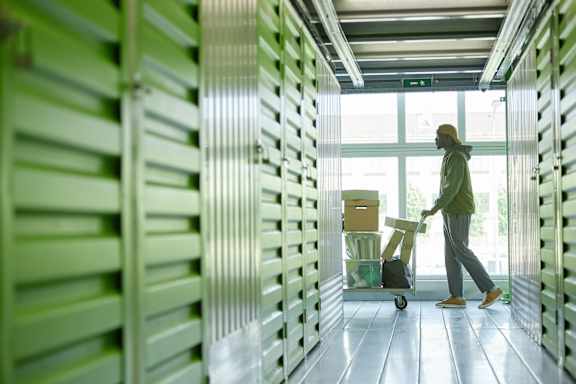 A person is walking with a trolley in a corridor with green walls.