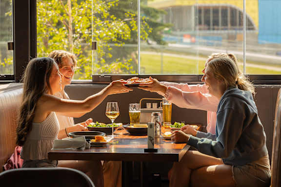 Two women toasting with drinks at a table in a restaurant.