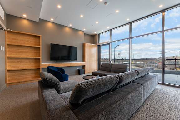 A modern living room with a large grey sofa and a wooden entertainment center.