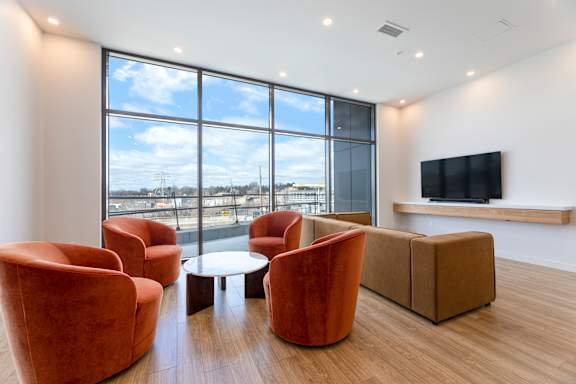 A living room with a large window, a sofa, a chair, a coffee table, and a television.