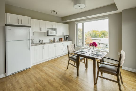 A kitchen and dining area with a table and chairs and a large window