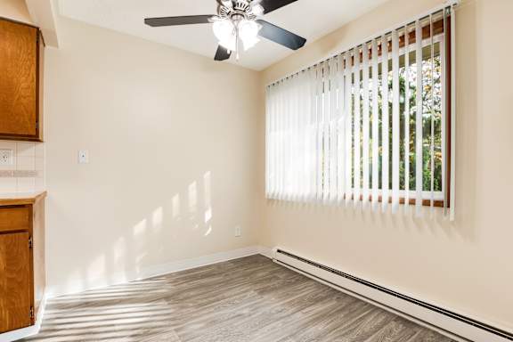 an empty living room with a window and a ceiling fan