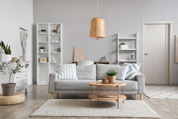 A living room with a grey sofa, a wooden coffee table, and a woven light fixture.