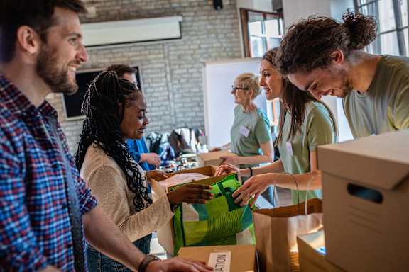 a group of people standing in a room with boxes and bags