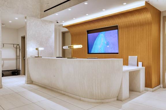 A reception area with a white reception desk and a television mounted on the wall.at 301E94, New York New York