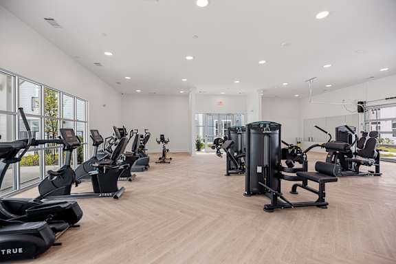 a spacious fitness room with cardio machines and weights  at Oak Grove at Blake Farm, North Carolina, 28411