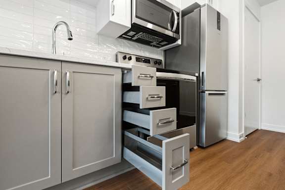 A kitchen with a refrigerator, microwave, and oven.