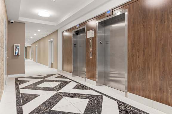 A hallway with marble tiles and elevators.