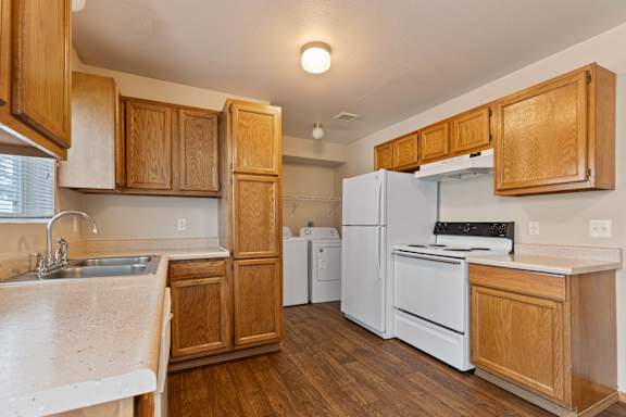 a kitchen with white appliances and wooden cabinets