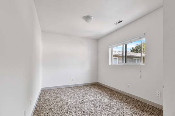 a bedroom with white walls and a window