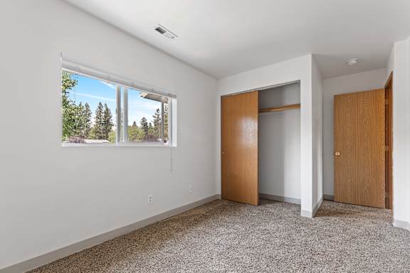 a bedroom with a large window and a closet