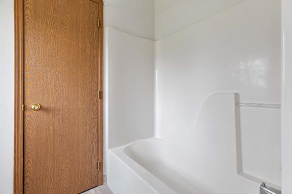 a bathroom with a white bathtub and a wooden door