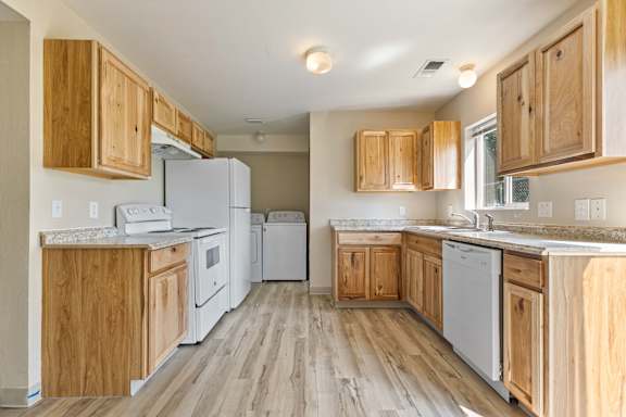 a kitchen with white appliances and wooden cabinets