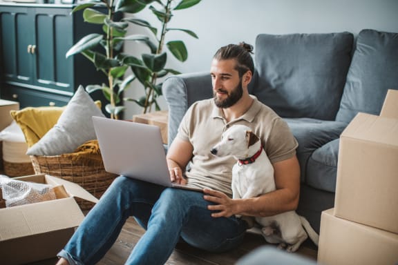 a man sitting on the floor with a dog and a laptop