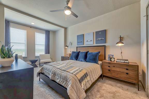 A bedroom with a bed, nightstand, and a plant.