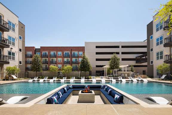 A large swimming pool with lounge chairs and a fountain in the middle.