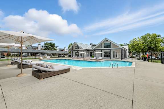 A large swimming pool surrounded by lounge chairs and umbrellas.