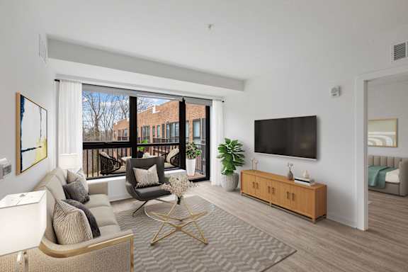 A living room with a white couch, a grey rug, a wooden coffee table, a TV, and a balcony with a view of a building.