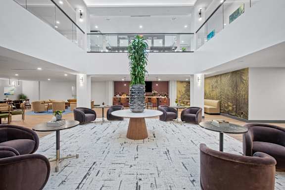 A large room with a stone floor and a tree in a vase.