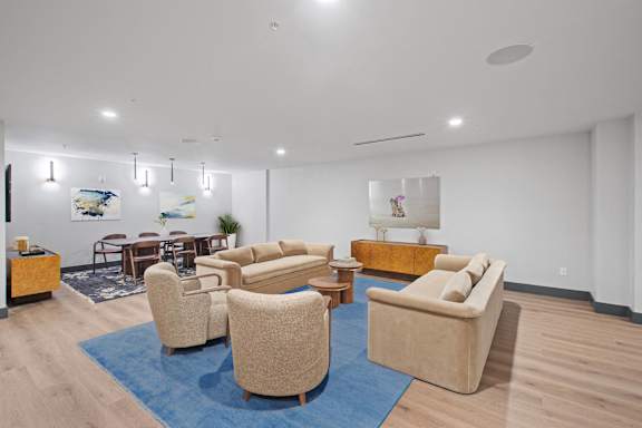 A living room with a blue rug and beige furniture.