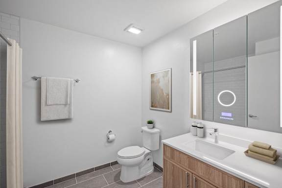 A modern bathroom with a toilet, sink, and mirror.